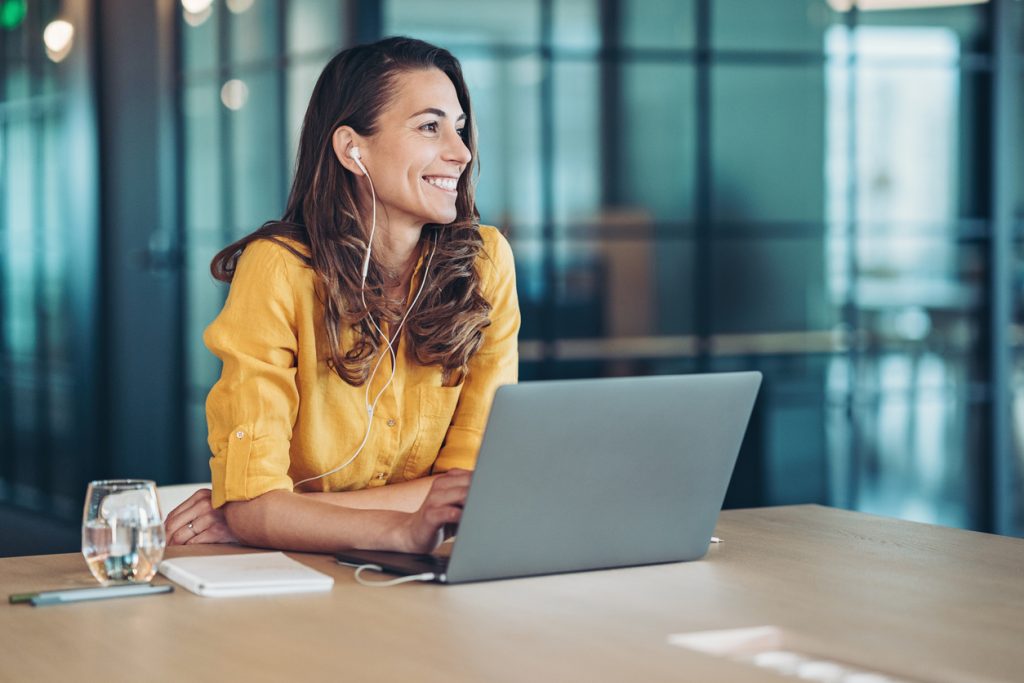 Smiling business woman with laptop and headphones | RiskSphere